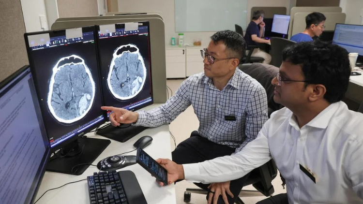 Robert Chen (left), head of the neuroradiology department at Singapore General Hospital and National Neuroscience Institute, reviewing the AI results and CT scans of patients with Sarat Kumar Sanamandra, senior consultant at the same department. ST PHOTO: GIN TAY